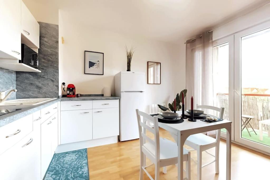 a kitchen with a table and a white refrigerator at Chaleureux et Cosy proche Gare in Massy