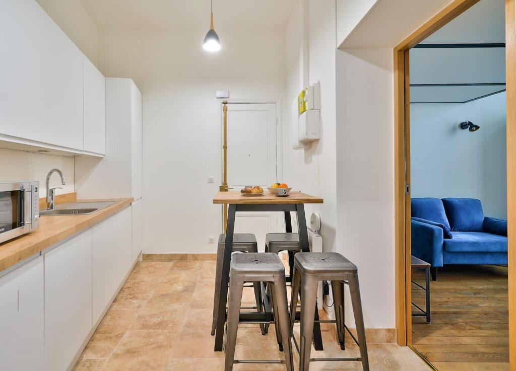 a kitchen with a table and stools in a room at GuestReady - Beautiful Apt near Paris Zoo in Paris