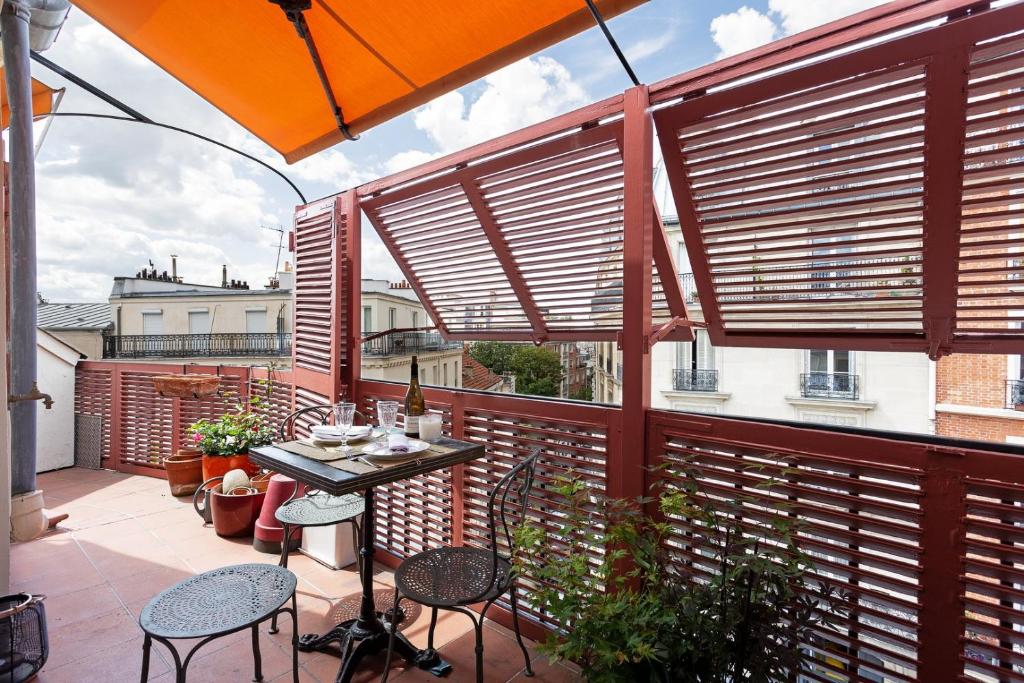 un patio avec une table, des chaises et un parasol dans l'établissement GuestReady - Charmant Apt. près du Sacré-Cœur, à Paris