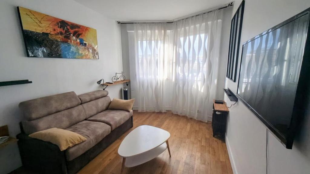un salon avec un canapé et une télévision à écran plat dans l'établissement GuestRead - Appt moderne près des Batignolles, à Paris