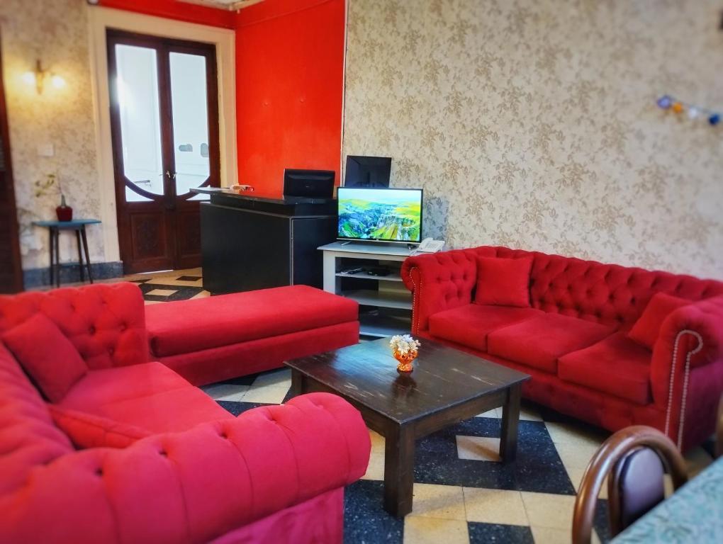 a living room with red couches and a tv at En La Plata Hostel El Pampa in La Plata