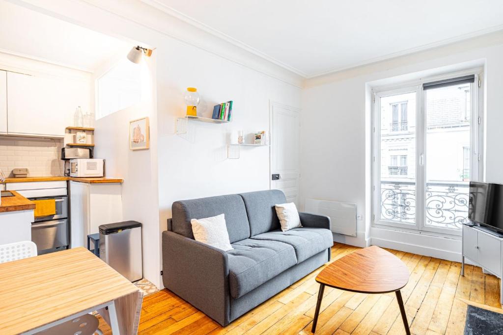 un salon avec un canapé et une cuisine dans l'établissement GuestReady - Charme et Confort dans le 11ᵉ arr., à Paris