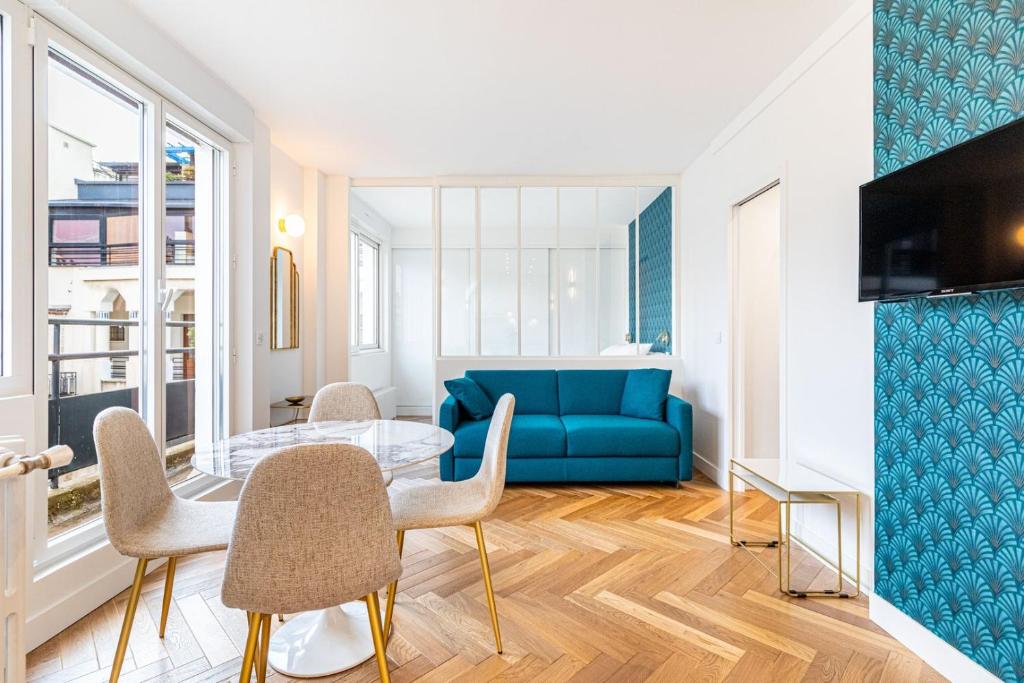un salon avec un canapé bleu et une table en verre dans l'établissement GuestReady - Appartement Grenelle, à Paris