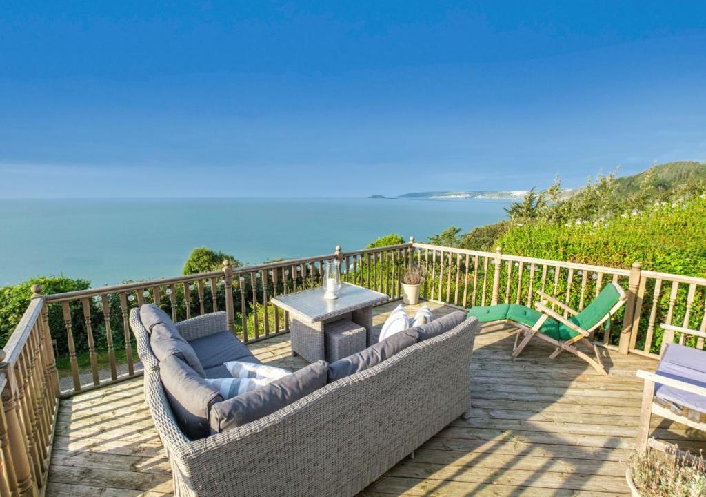 a deck with a couch and a table and chairs at Penrose in Downderry