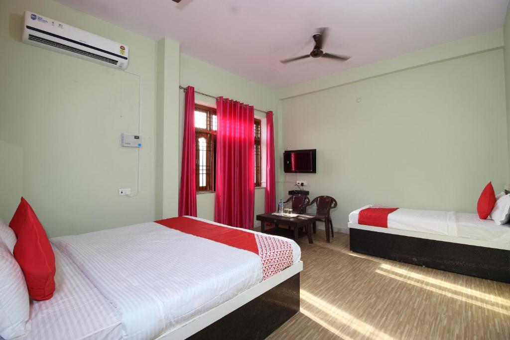 a bedroom with two beds with red curtains at Super Capital O Hotel Paradise Residency in Rāmnagar