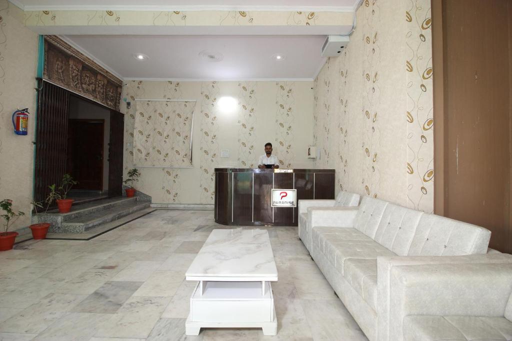 a living room with a couch and a person in the background at Super Capital O Hotel Paradise Residency in Rāmnagar
