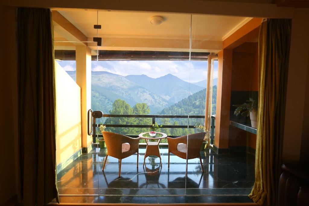a balcony with a table and chairs and a view of mountains at The Byke Nature Vilas Pure Veg in Shimla