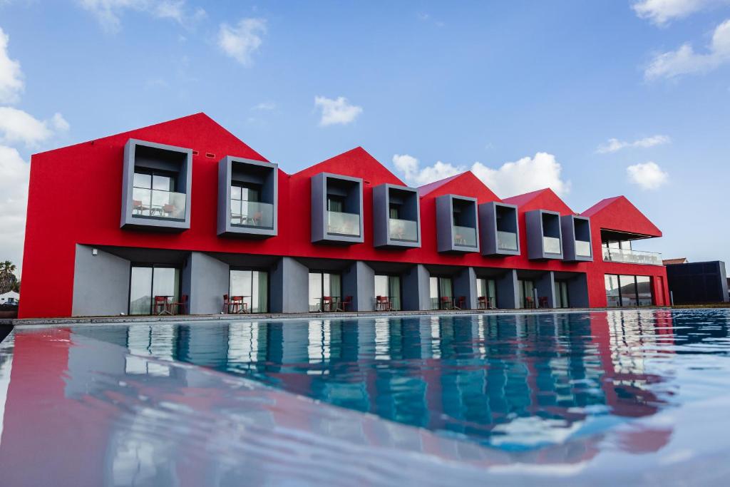 a red building next to a swimming pool at Pico Terramar & SPA in Areia Larga