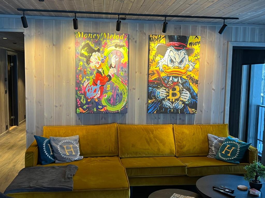 ein gelbes Sofa in einem Zimmer mit Gemälden an der Wand in der Unterkunft Fjellandsbyen 307 in Hemsedal