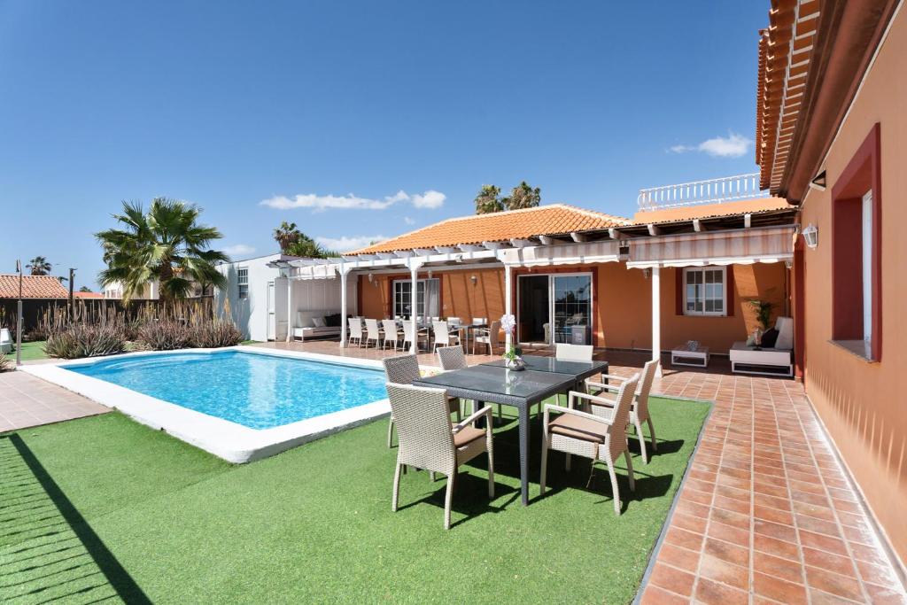 a patio with a table and chairs next to a swimming pool at Villa Golf del Sur in San Miguel de Abona
