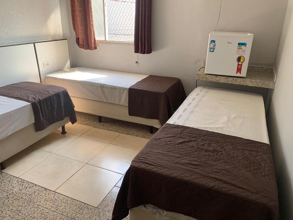 a small room with two beds and a window at Hotel Village in Sao Paulo