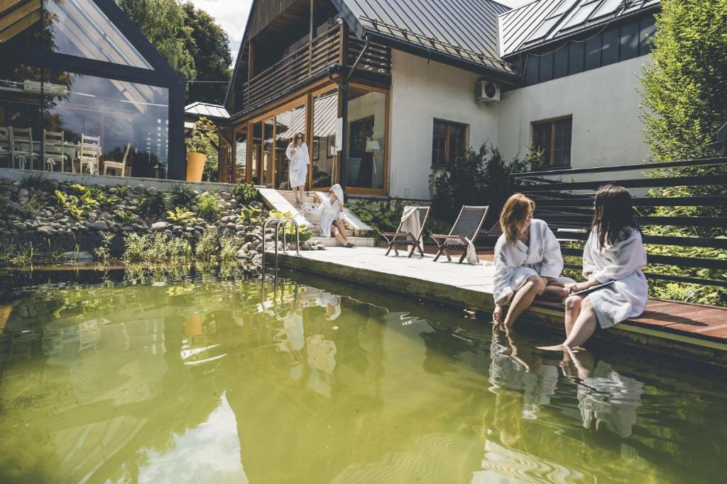 ナウェンチュフにあるŁubinowe Wzgórze - Wioska Zdrowiaの家の池の横に座る二人の女性