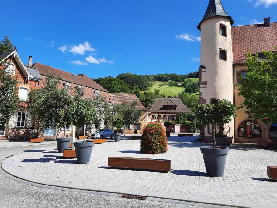 a town square with a clock tower and a building at LE CHANT DE LA RIVIERE in Sainte-Marie-aux-Mines
