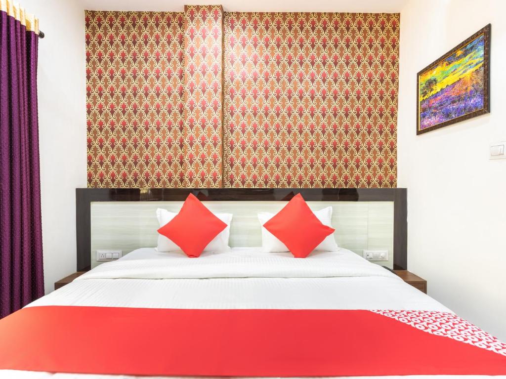 a bedroom with a large bed with red pillows at Flagship Savitri Regency in Bhopal