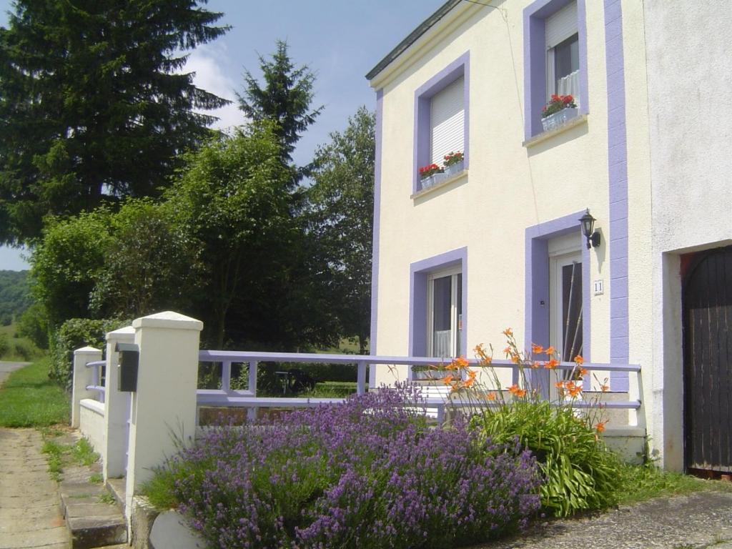 una casa blanca con flores púrpuras delante de ella en Aux 2 cerisiers, en Virton