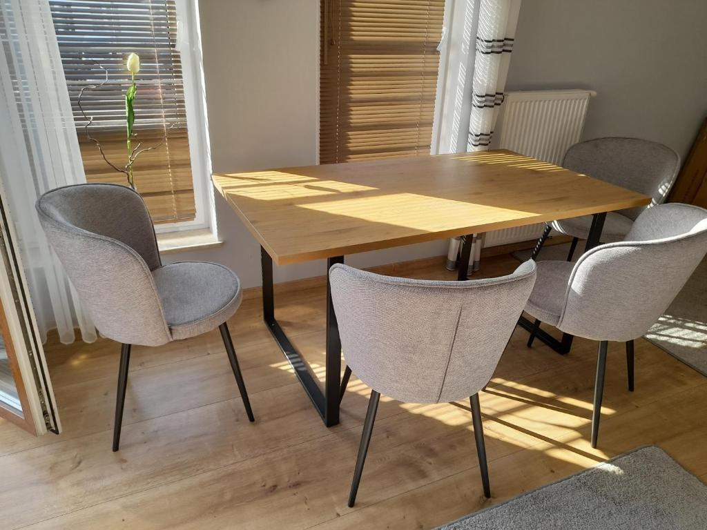 een houten tafel en stoelen in een kamer met een raam bij Apartament Leśna 18 in Olsztyn