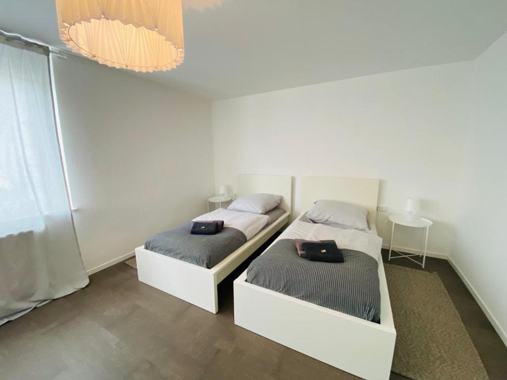 two beds in a white room with at Modernes, vollmöbliertes Apartment in ruhiger Lage in Hemer