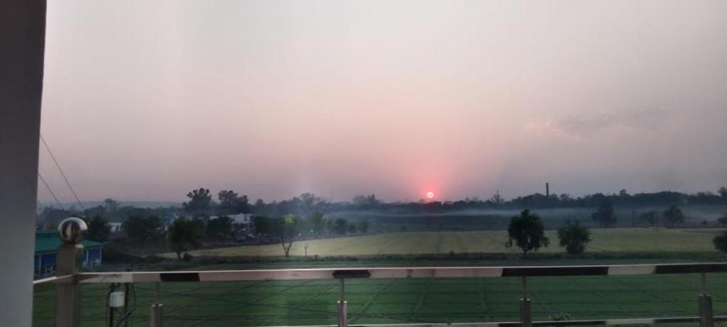 Blick auf ein Feld mit Sonnenuntergang im Hintergrund in der Unterkunft Sonakshi Homestay in Birbhaddar