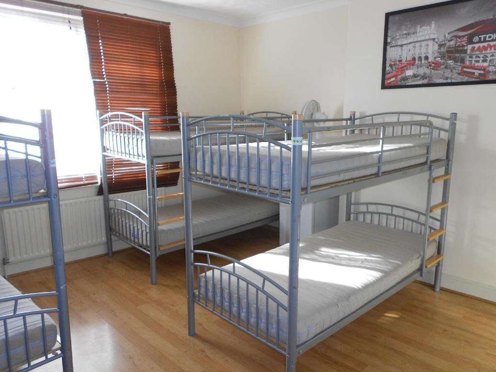 three bunk beds in a room with a window at 24/7 London Hostel in London