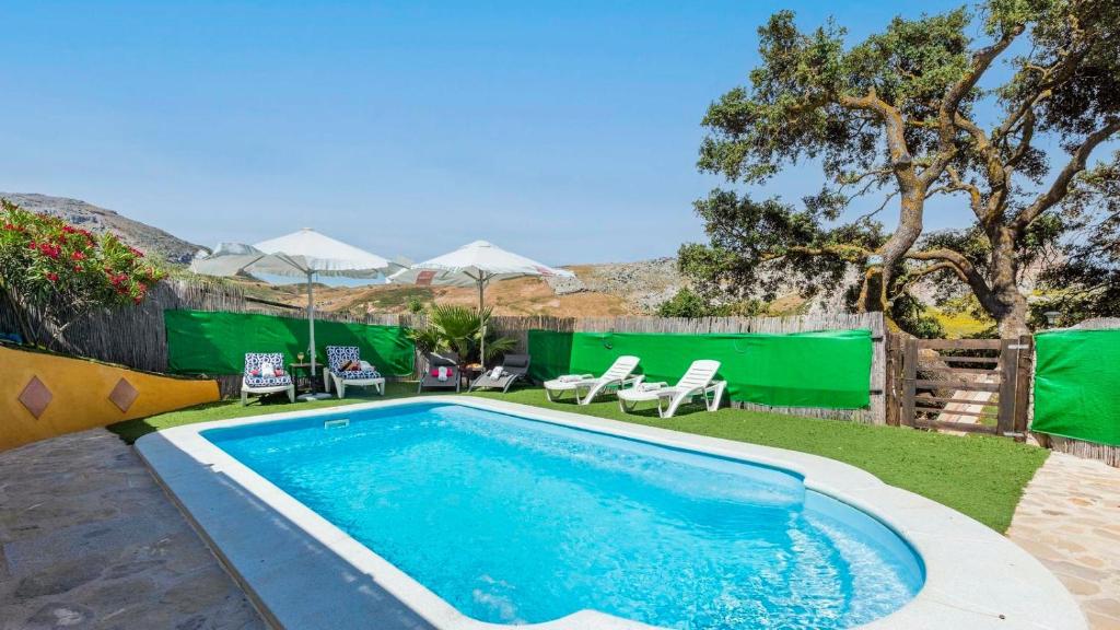 a swimming pool in a yard with chairs and umbrellas at Casa Gonzalez Villanueva de la Concepcion by Ruralidays in Villanueva de la Concepción