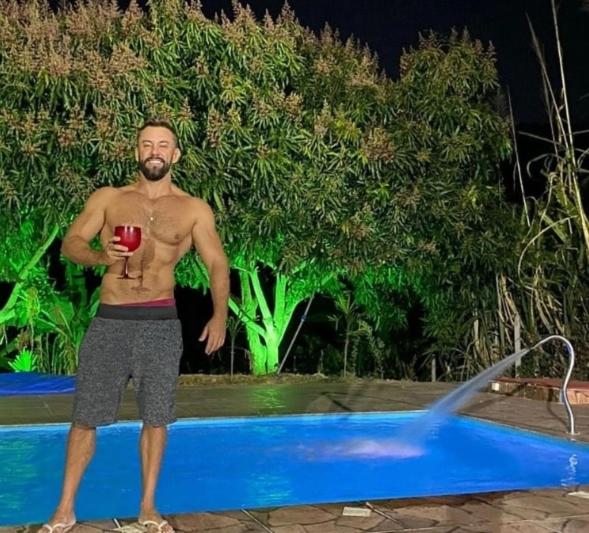 Ein Mann, der ein Glas Wein neben einem Pool hält. in der Unterkunft SITiO SONHO DE CRIANÇA in Santa Luzia
