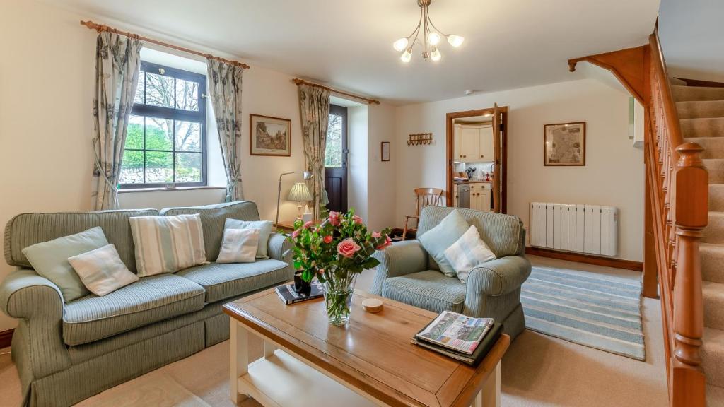 a living room with two couches and a table at Wye Cottage near Hassop in Eyam