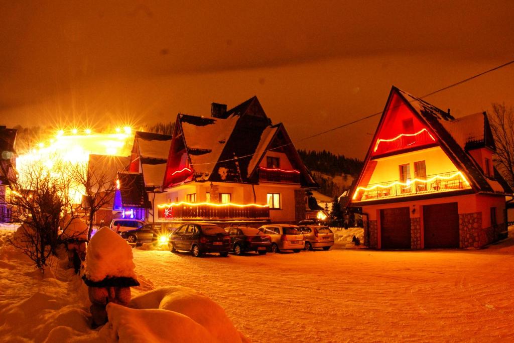 ザコパネにあるHanusina Chałupa Wynajem pokoiの雪中のクリスマス灯を持つ家屋群