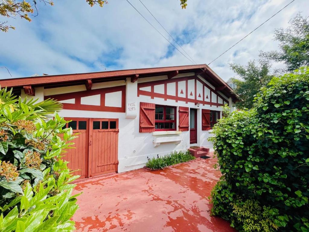 une maison blanche et rouge avec un garage rouge dans l'établissement Maison Basque avec Terrasse, Clim, et Wi-Fi à 600m de la Plage - Arcachon - FR-1-433-69, à Arcachon