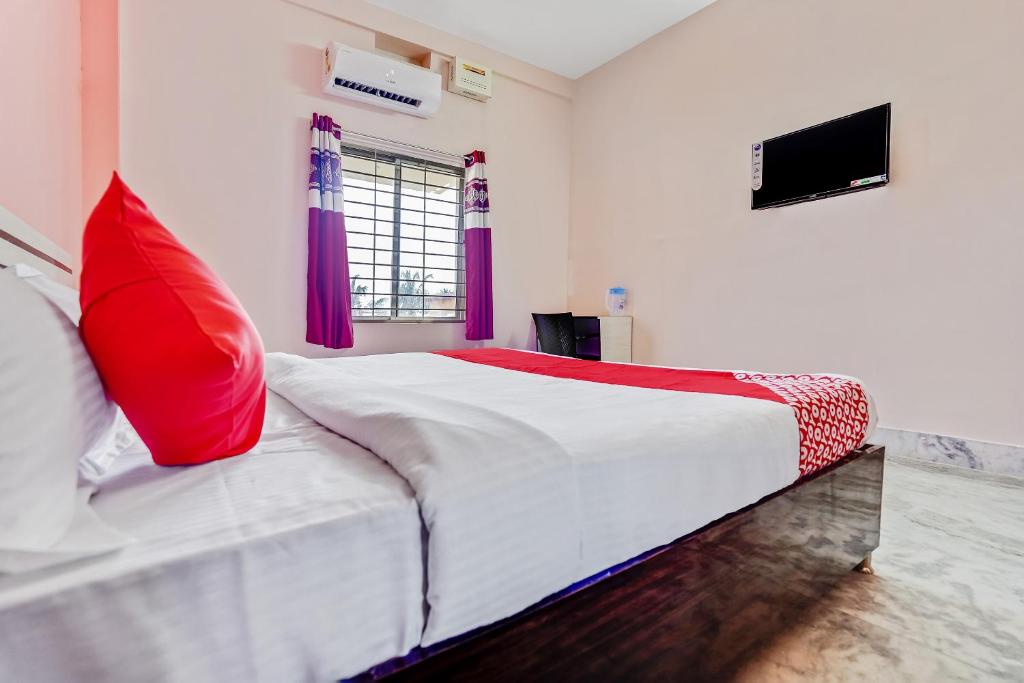 una camera da letto con un grande letto con un cuscino rosso di OYO Satya Homes a Khandagiri