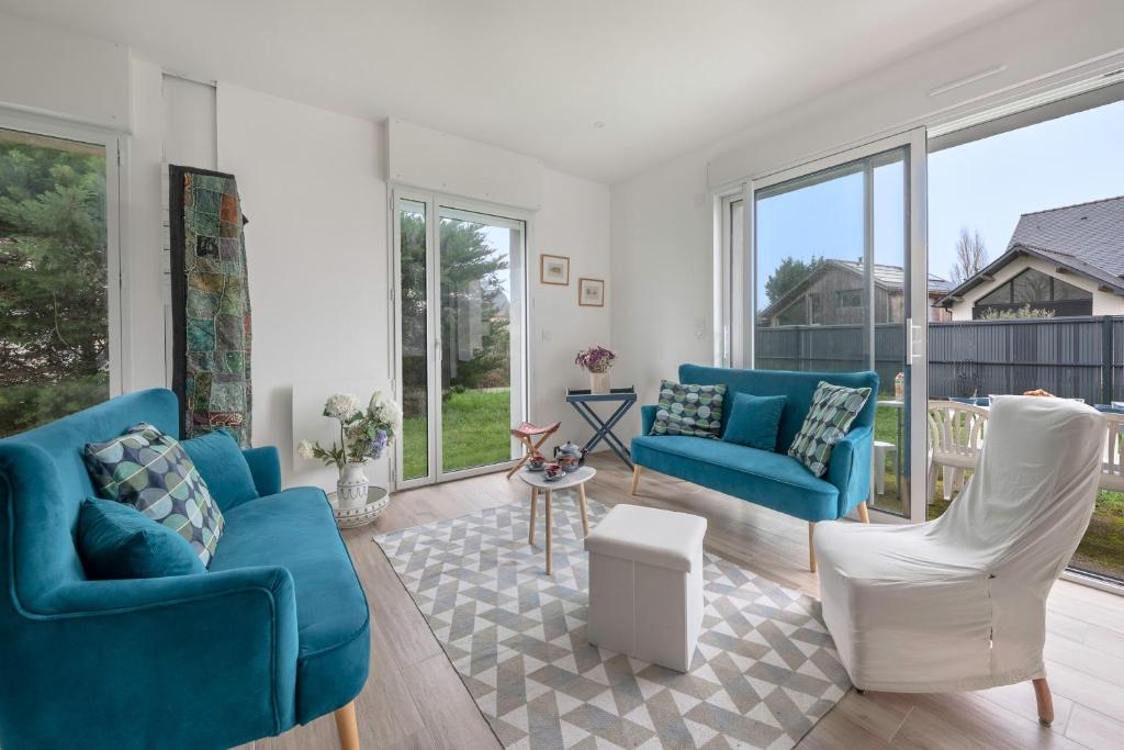een woonkamer met blauwe stoelen en ramen bij Confort et modernité dans cette jolie maison in Le Pouliguen