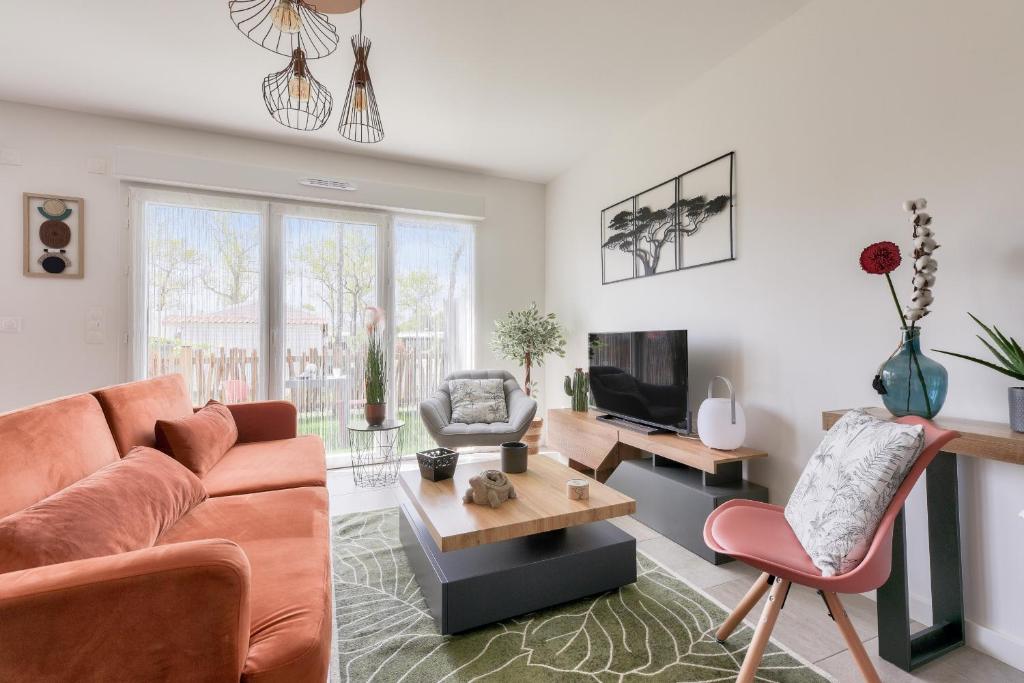 un salon avec un canapé et une télévision dans l'établissement Jolie maison avec terrasse à Andernos-les-bains, à Andernos-les-Bains