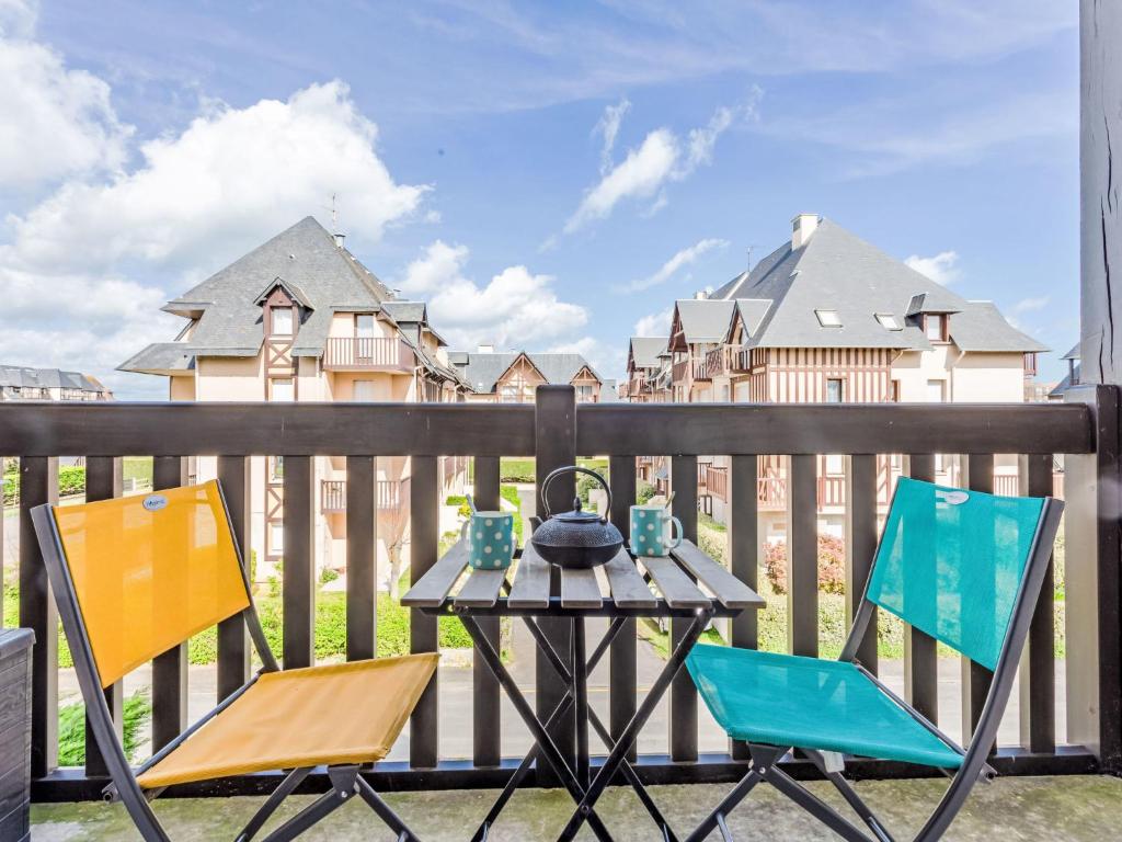 a table and two chairs on a balcony with buildings at Apartment Le Clos Mathilde-18 by Interhome in Cabourg