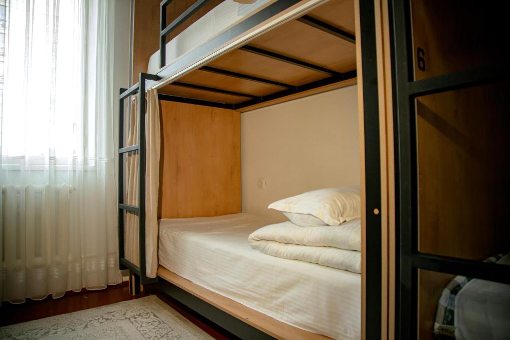 a bedroom with a bunk bed with white sheets at Ayla Hostel in Osh