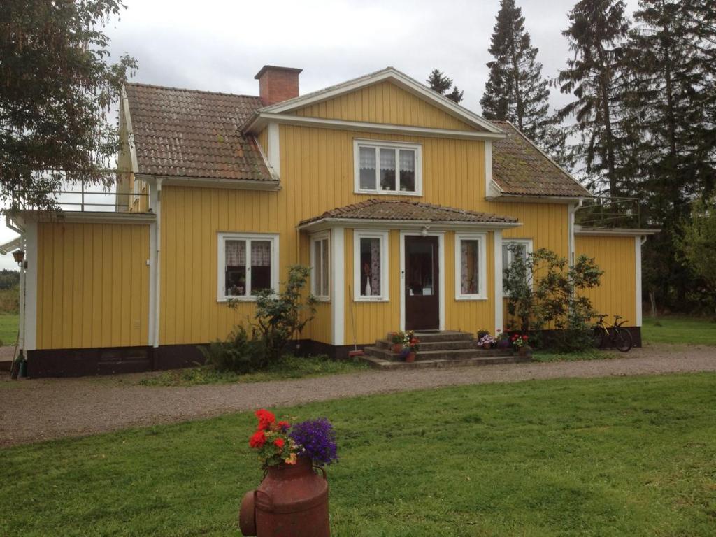 una casa amarilla con flores en un patio en Marielund Gård en Skara