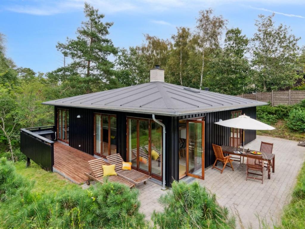 a black house with a patio and a table at Holiday Home Jonce - 250m from the sea in Sealand by Interhome in Vejby