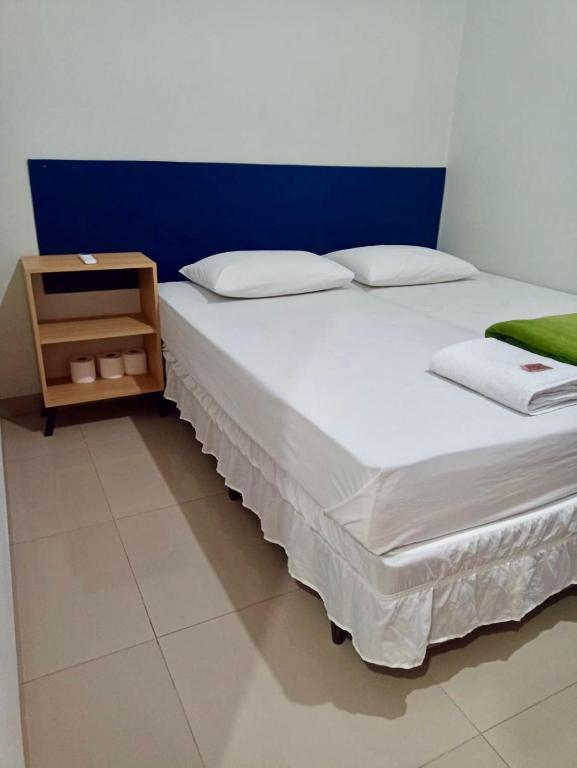 a bed in a room with a night stand next to it at AP 2 quartos, 1 ar condicionado, com cozinha de uso exclusivo in Sorriso