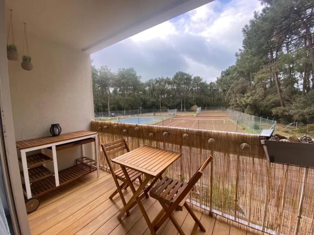 einen Balkon mit einem Tisch und Stühlen sowie einen Tennisplatz in der Unterkunft Appartement au Parc de la Grange in Jard-sur-Mer