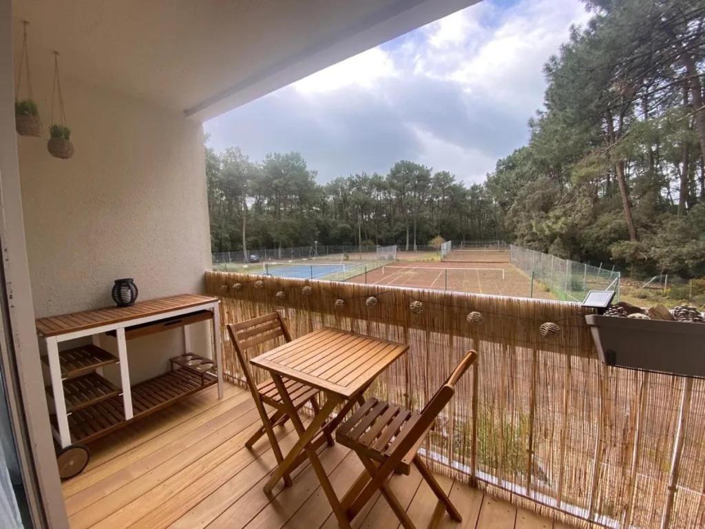 a balcony with a table and chairs and a tennis court at Appartement au Parc de la Grange in Jard-sur-Mer