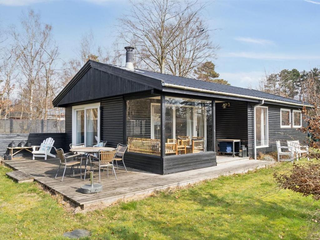 uma casa com um deque com uma mesa e cadeiras em Holiday Home Josef - 1-4km from the sea in Sealand by Interhome em Rørvig