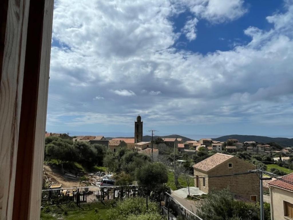 een uitzicht vanuit een raam van een stad met een klokkentoren bij Guetali du Village in Monacia-dʼAullène