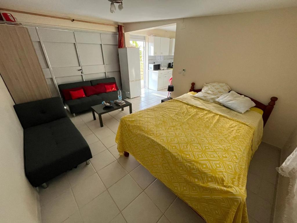 1 dormitorio con cama amarilla y sofá en Studio avec jardin clos et wifi a Le Lamentin a 5 km de la plage en Le Lamentin