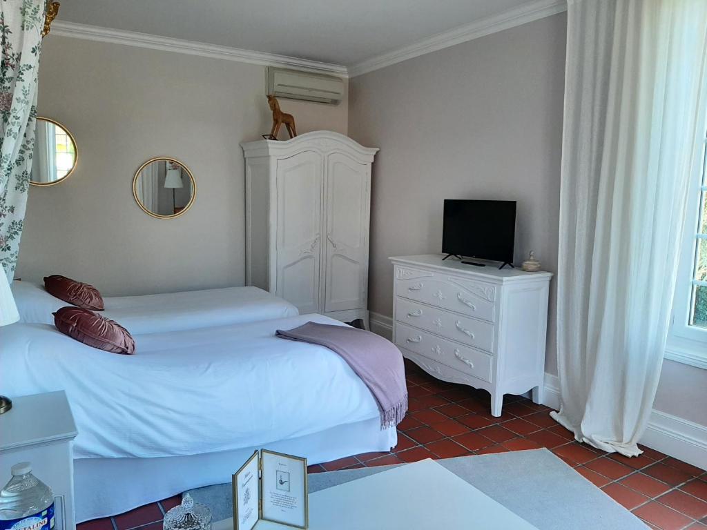 a bedroom with two beds and a television on a dresser at Maison Coqueréaumont in Montagne