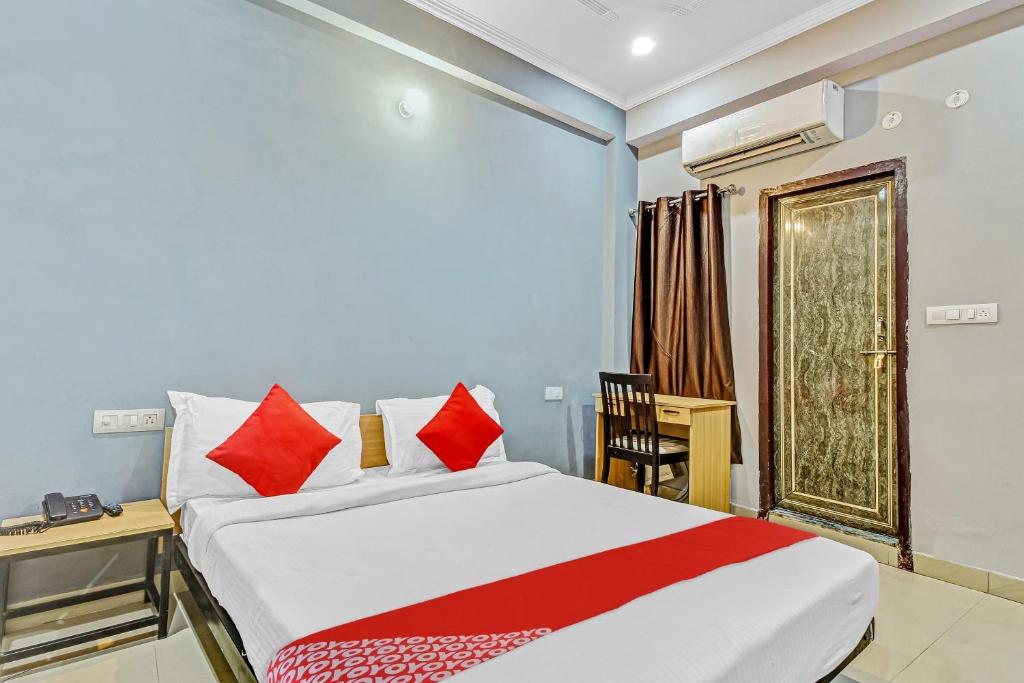 Un dormitorio con una cama con almohadas rojas y una ventana en Orphic Inn Near Munshi Pulia Metro Station, en Chinhat