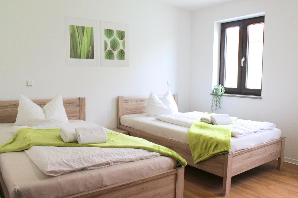 two beds in a room with white walls at Hotel am Wittelsbacher Markt by greenpartment in Langquaid