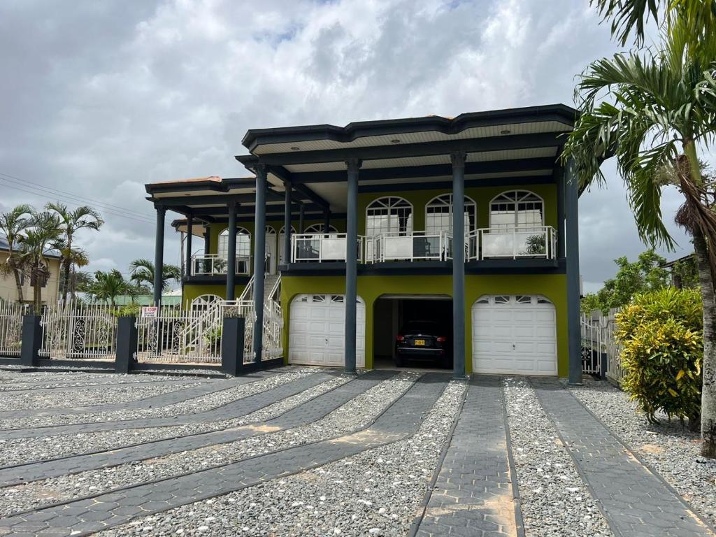 a yellow house with two white garage doors at Luxueus appartement Wanica, Welgedacht C in Wanica