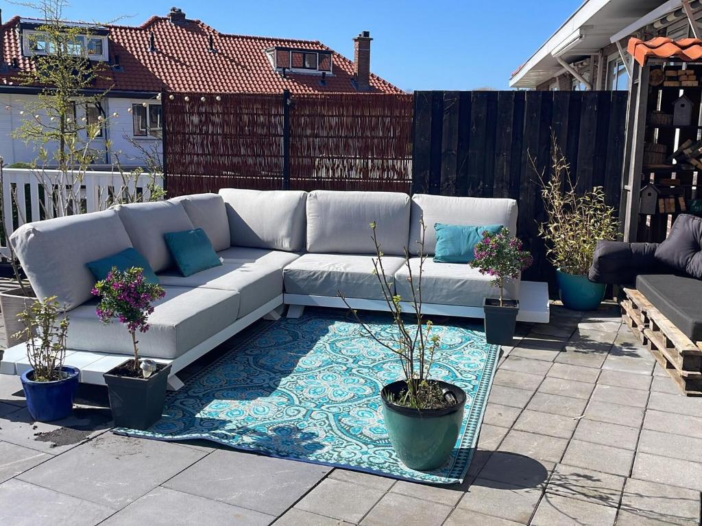um sofá branco sentado num pátio com vasos de plantas em Luxury holiday home in The Hague with a beautiful roof terrace em Haia