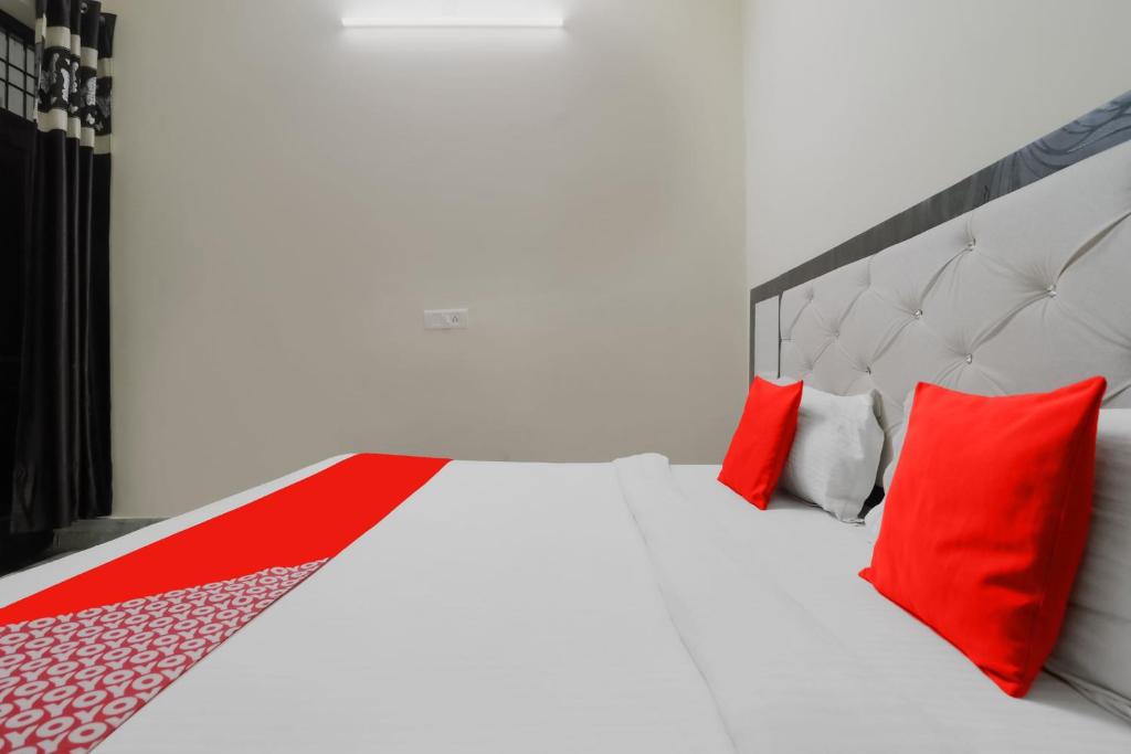 een slaapkamer met een wit bed met rode kussens bij OYO Hc Plaza in Kharar