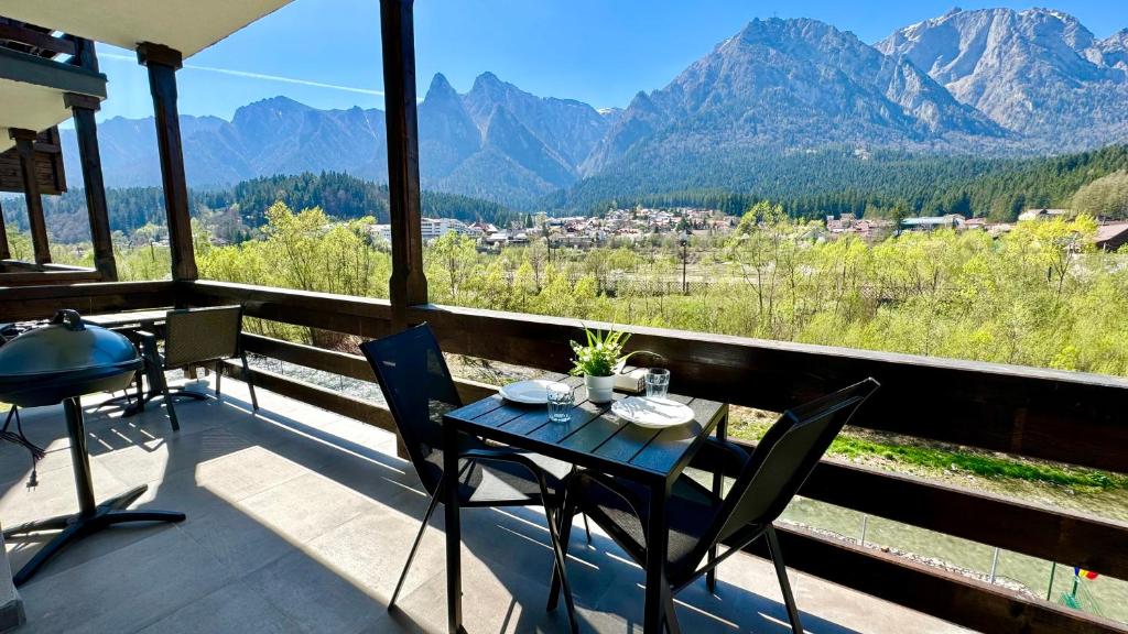 una mesa y sillas en un balcón con montañas en Busteni Mountain View Suites by the River - EV Plug en Buşteni