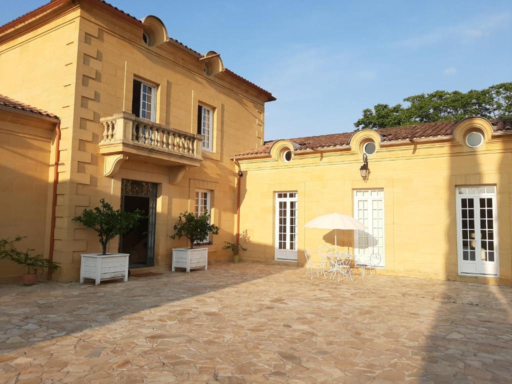a large yellow building with a balcony and an umbrella at Maison Coqueréaumont in Montagne