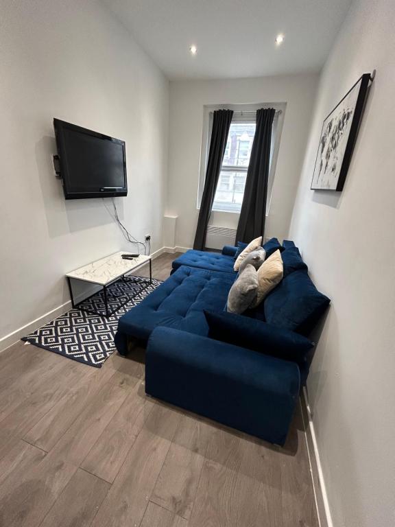 a living room with a blue couch and a flat screen tv at Central locations 1 bed apartments sleeps 4 in London